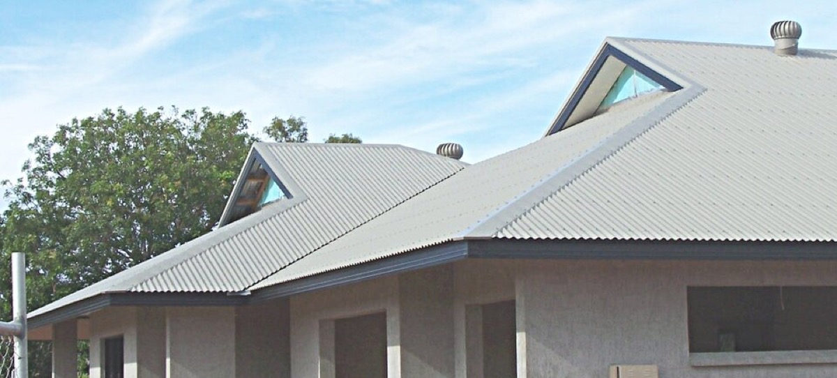 Corrugated metal roofing being applied to a gabled house roof